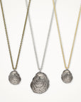 Three shell pendant necklaces on gold, silver, and bronze chains against a white background.