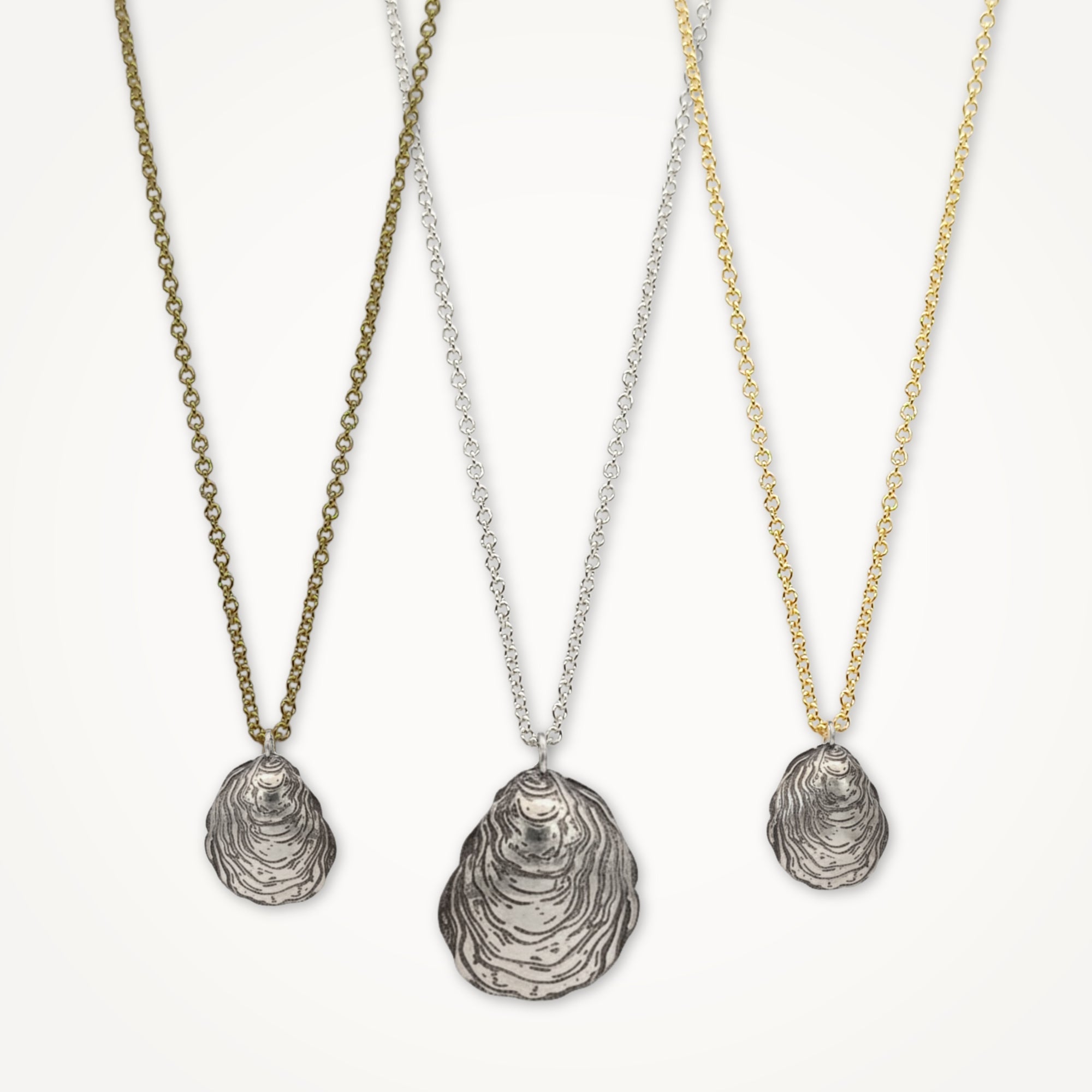 Three shell pendant necklaces on gold, silver, and bronze chains against a white background.